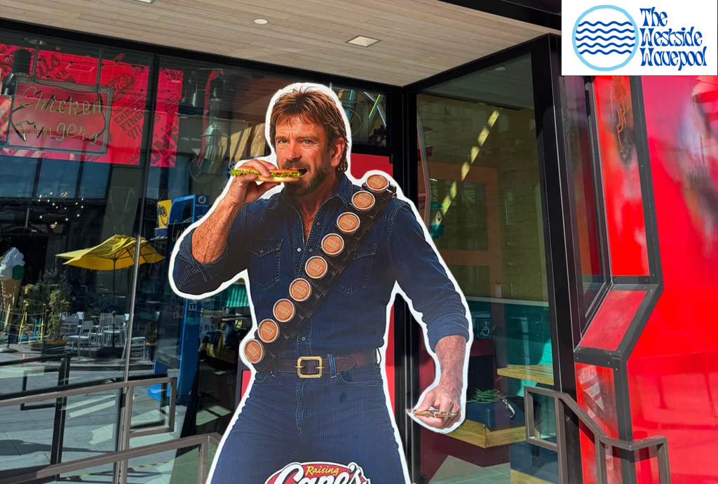 A life-sized cutout of a man holding a sandwich, posing in front of a restaurant with a sign that reads 'Chicken Fingers'. The backdrop features bright colors and outdoor seating.